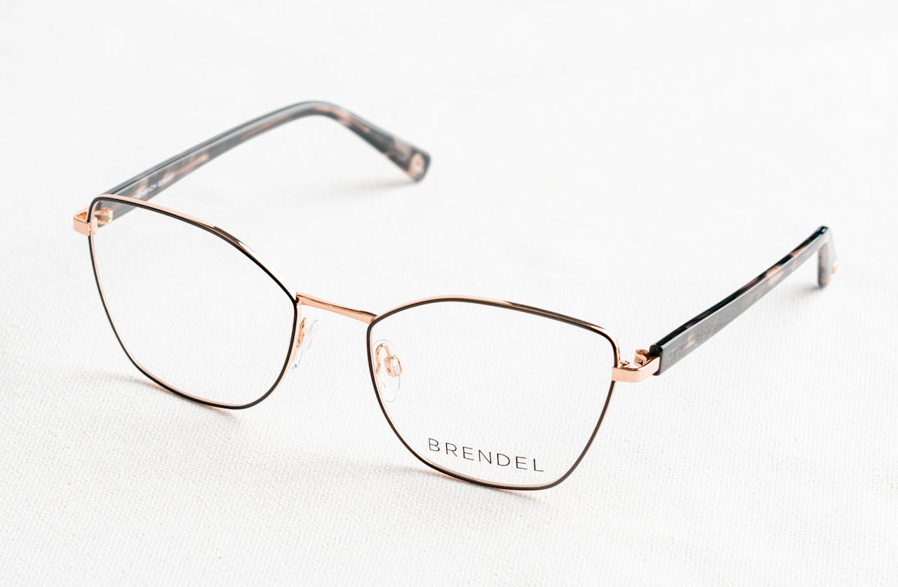 about-03 Close-up of stylish gold eyeglasses with 'BRENDEL' branding on a clean white surface.