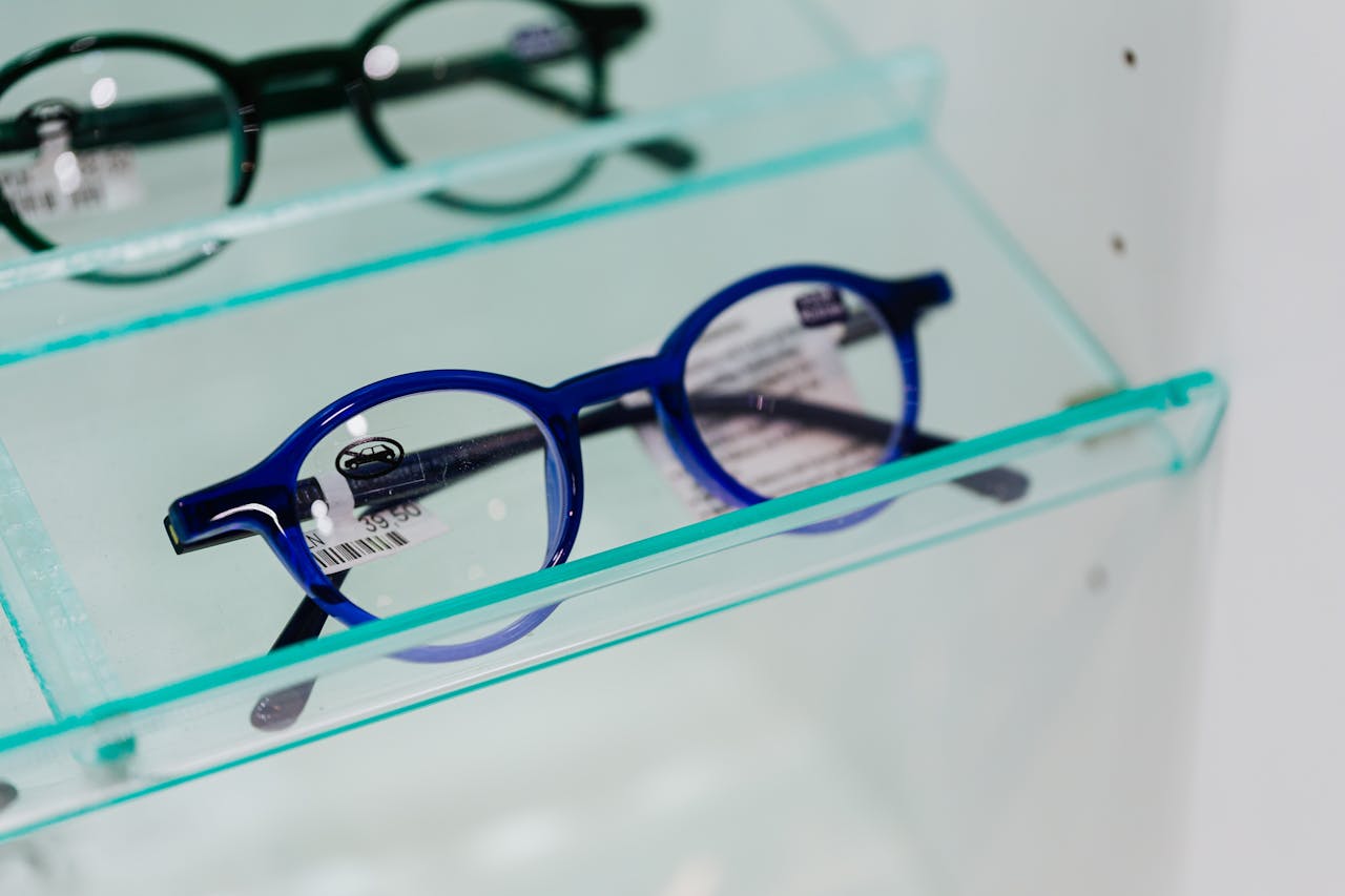 about-04 Modern blue eyeglasses showcased in a glass display case, perfect for fashion and optics themes.